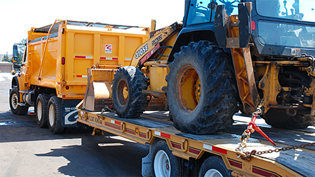 a piece of heavy equipment displaying proper load securement on a flatbed truck